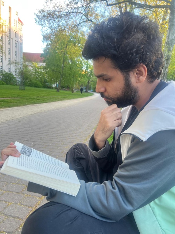 Akif reading a book in a park